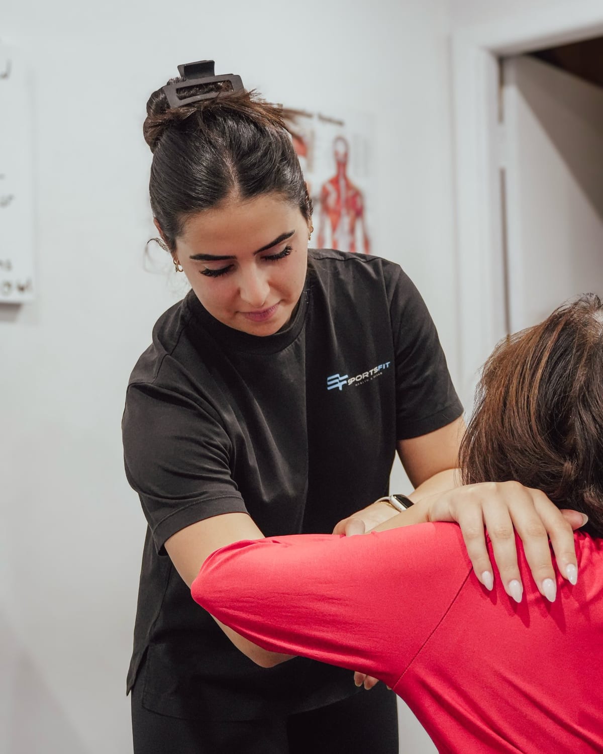 Physiotherapist mobilising a patient shoulder, one hand on the shoulder blade and the forearm supporting the arm