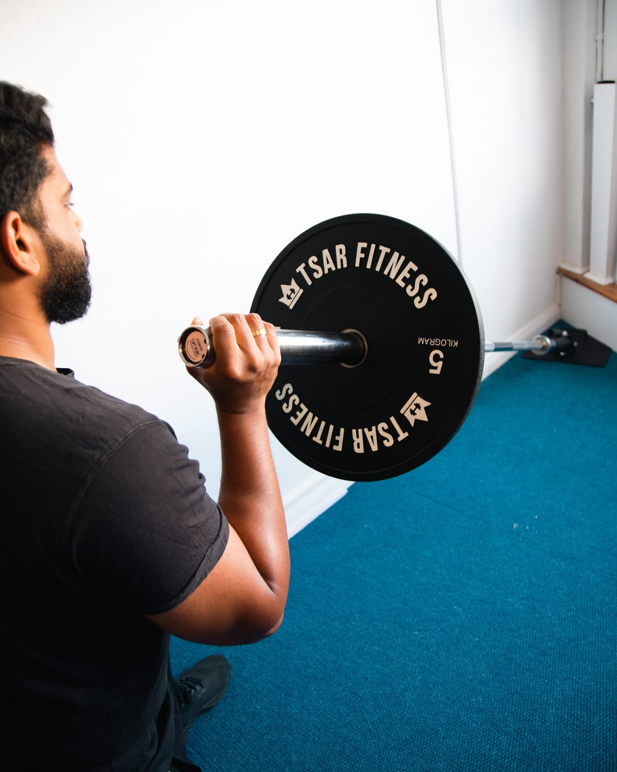 Half-kneeling landmine press with an anchored barbell, working the shoulder overhead