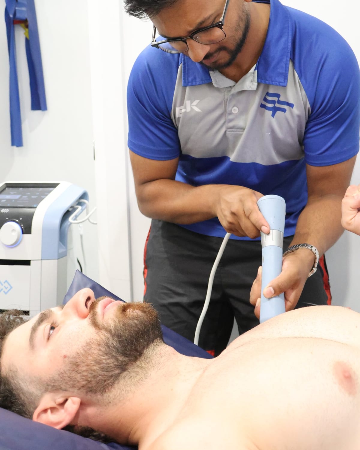 Shockwave therapy handpiece applied to a patient shoulder at SportsFit Five Dock